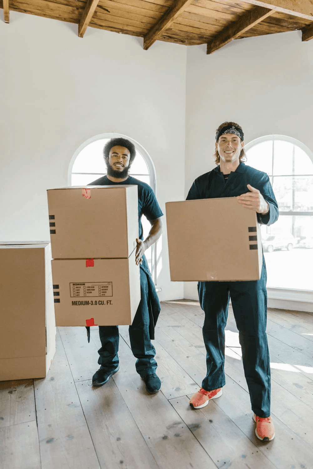 Two professional movers carry packed boxes.png